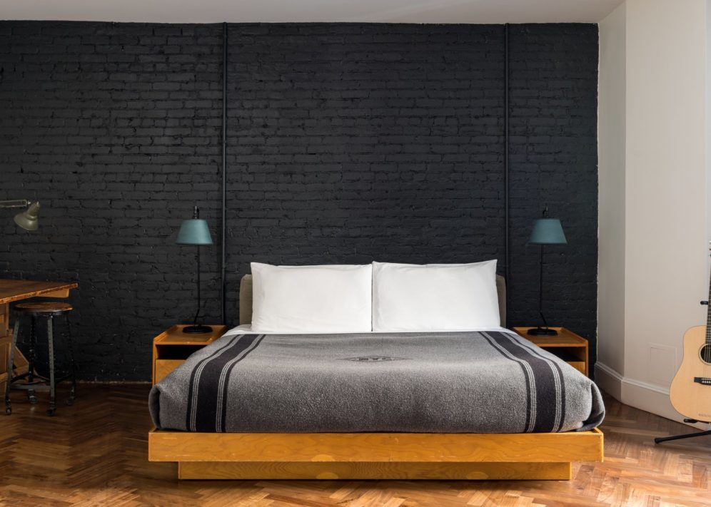 A black exposed brick wall is juxtaposed with bight, polished wooden flooring