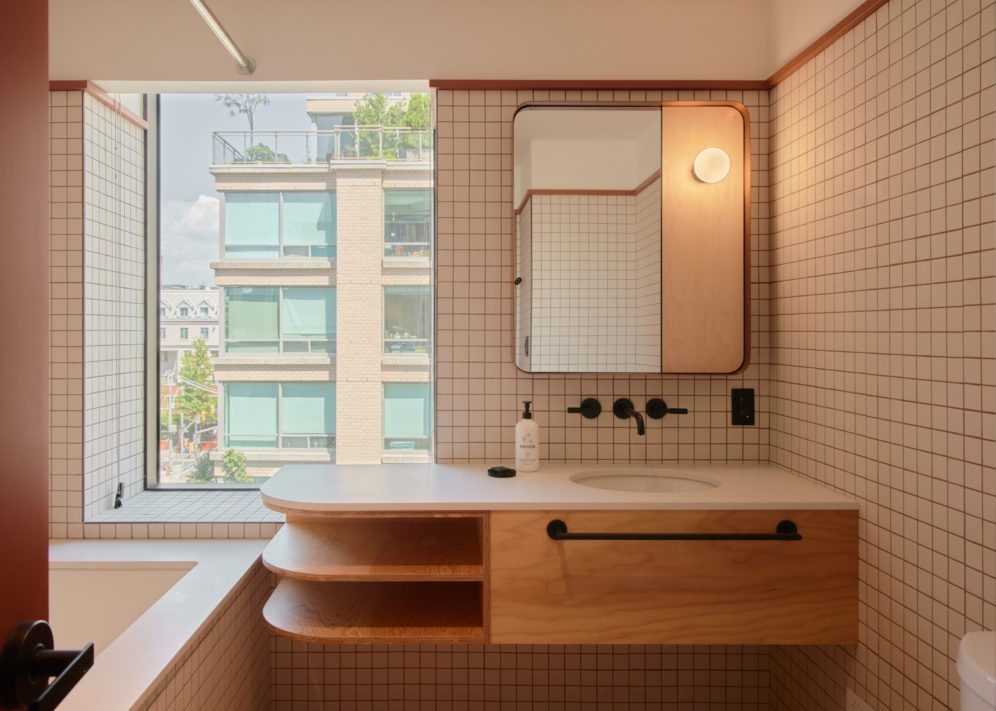 A modern white tiled bathroom features a spacious vanity area and large window