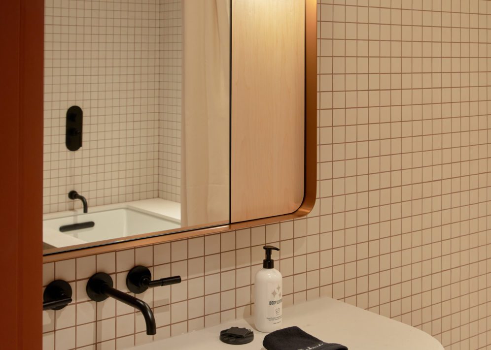 A modern white tiled bathroom features a deep bathtub
