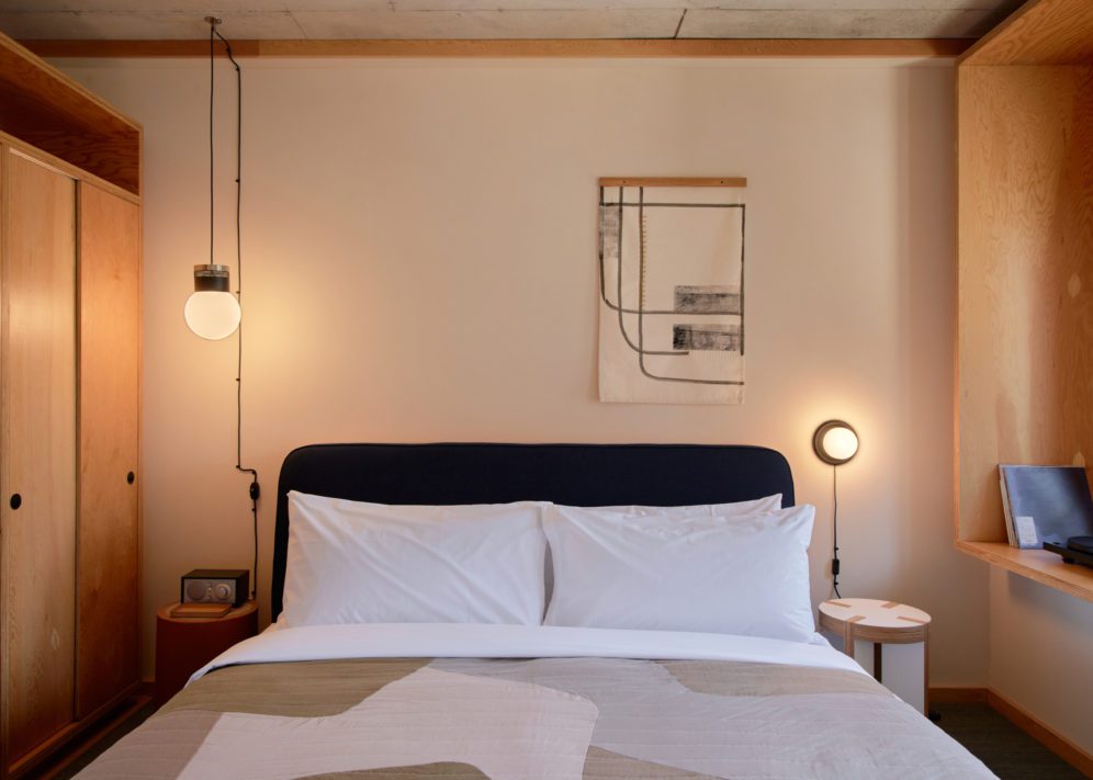 A bed sits in between two modern lights, providing a sense of ambience and calm