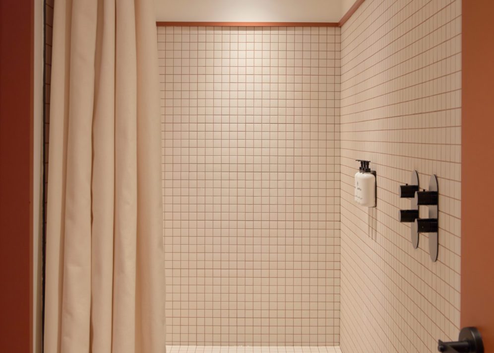 A modern white tiled bathroom features a spacious shower
