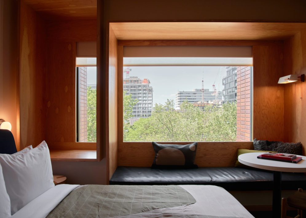 A wood paneled room features a black leather seating area under a window featuring greenery