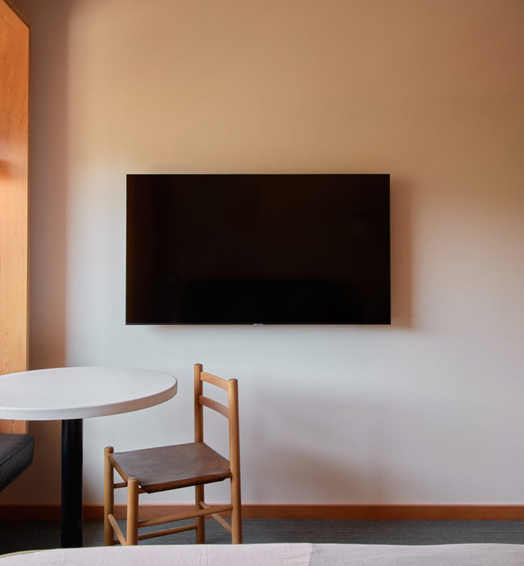 A television sits against a wall, and to its left is a standing closet for hanging clothes